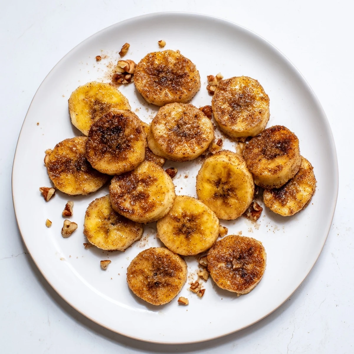 Stack of tender pan fried cinnamon bananas stacked high, their golden brown exteriors glistening under warm kitchen lighting