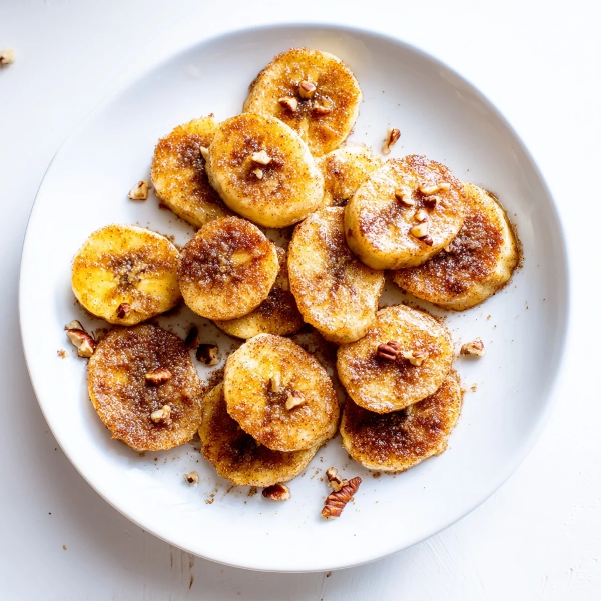 Skillet filled with warm brown sugar coated banana slices bubbling in butter with a dusting of fragrant ground cinnamon