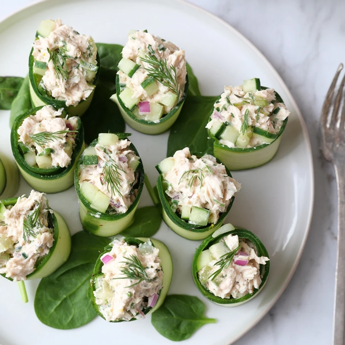 Fresh cucumber ribbons rolled around creamy chicken salad mixture, a light low-carb appetizer plated for serving