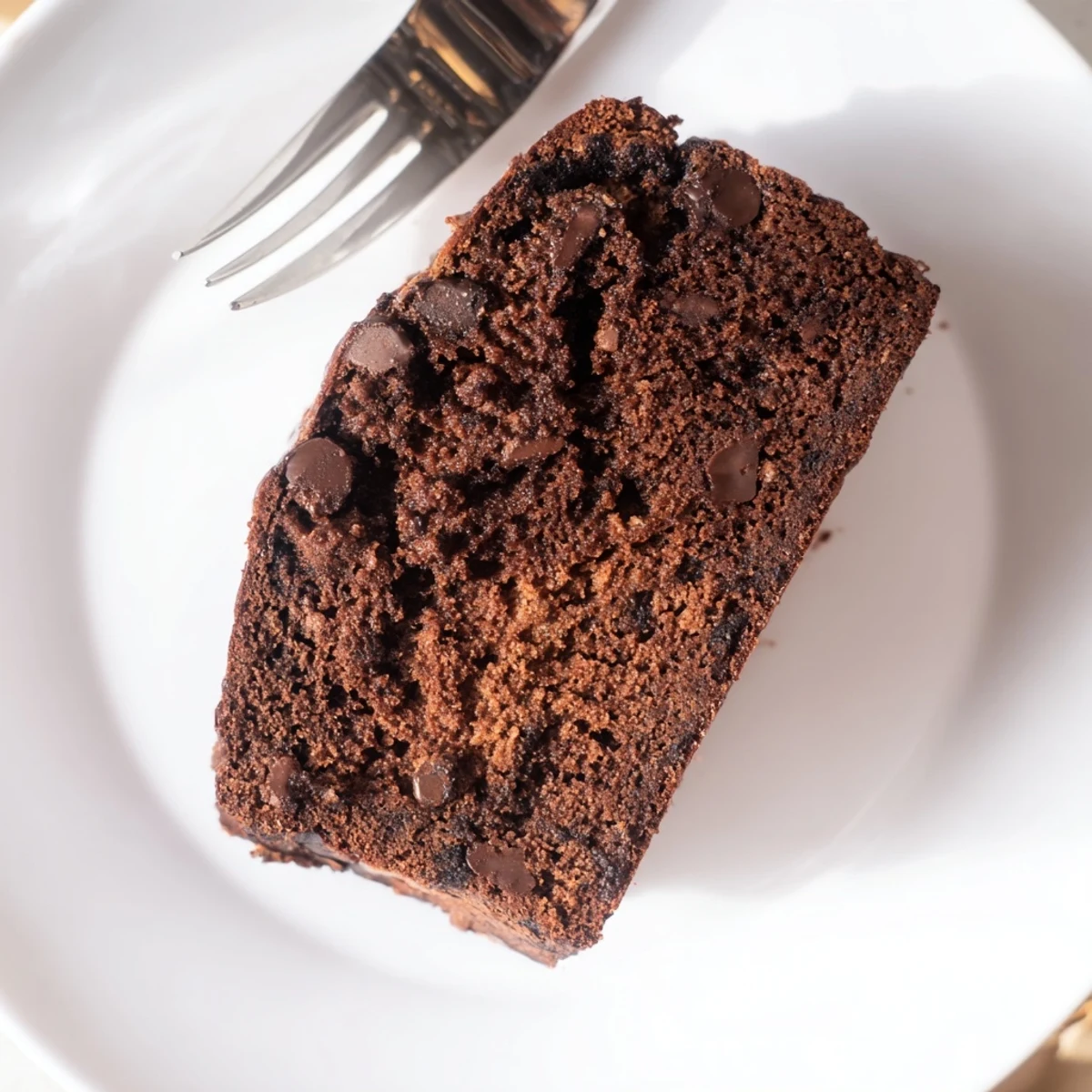 Warm loaf of chocolate espresso banana bread dusted with cocoa powder on wooden board