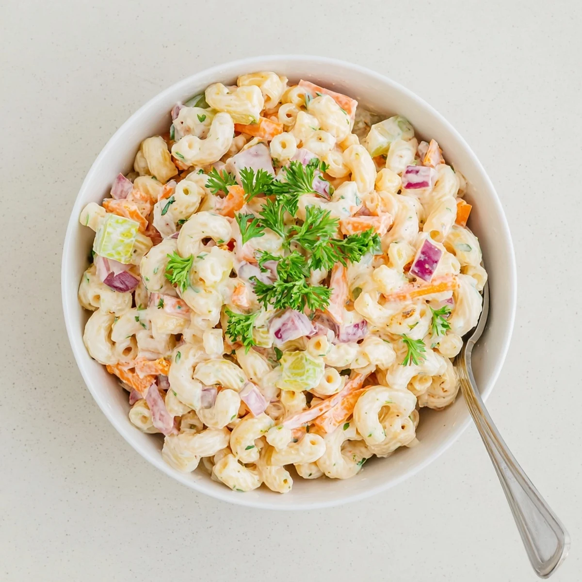 Heaping scoop of Tangy And Creamy Macaroni Salad topped with fresh parsley garnish