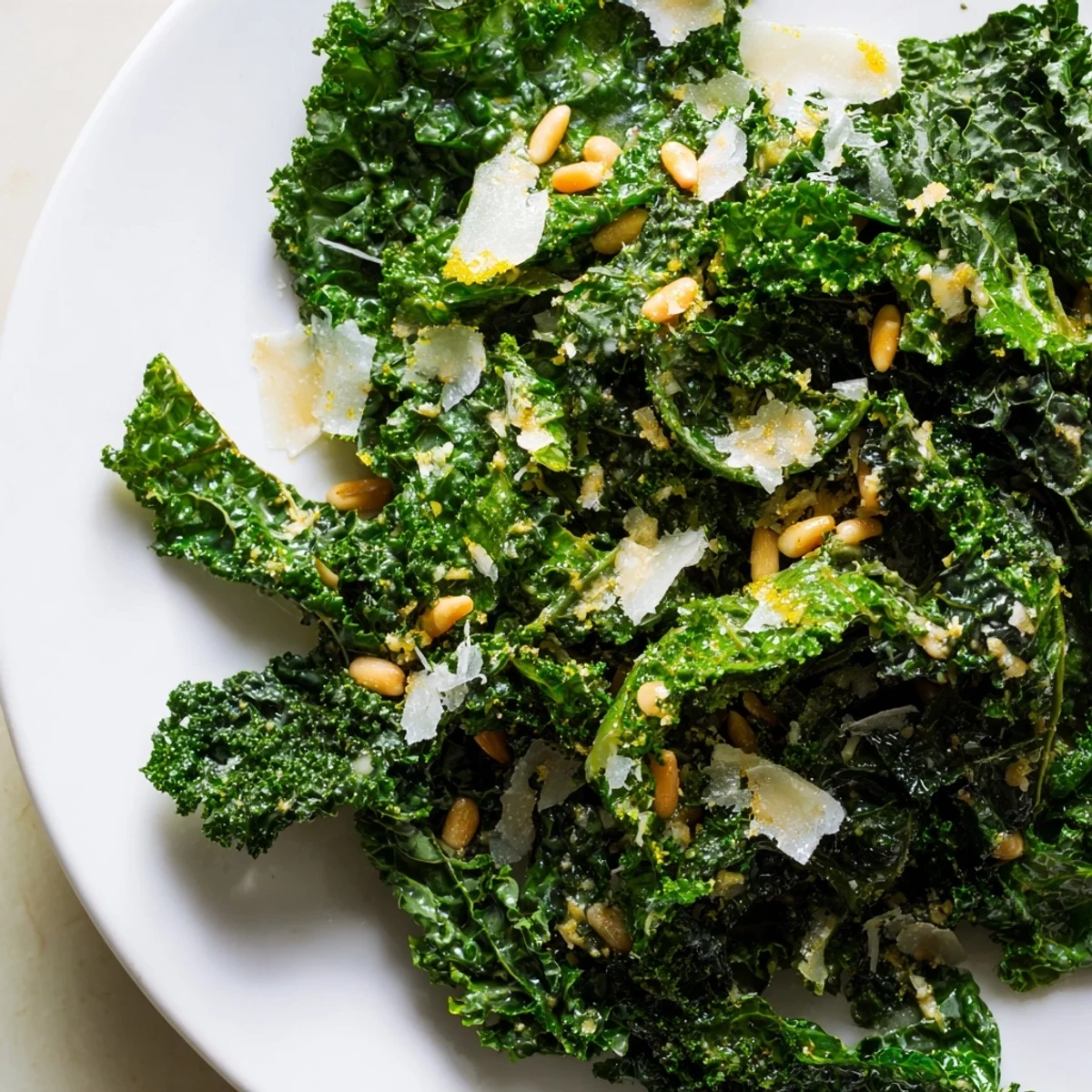 Crispy Garlic Lemon Parmesan Kale Salad topped with toasted pine nuts and shaved cheese.