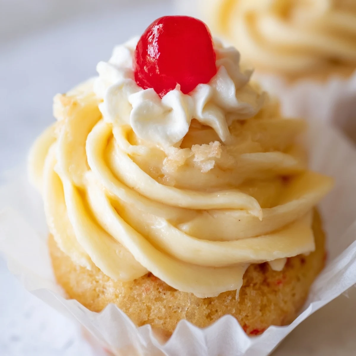 Fresh banana milkshake cupcakes with swirled buttercream frosting served on a rustic white ceramic plate