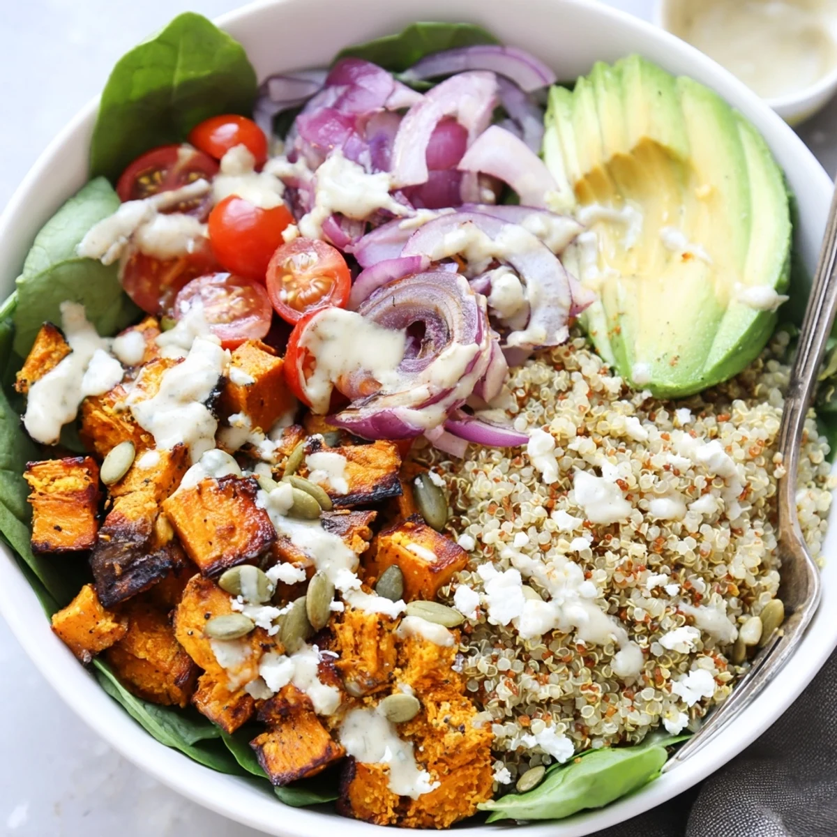 Bright Roasted Sweet Potato Quinoa Salad Bowl piled with fluffy quinoa, greens, feta