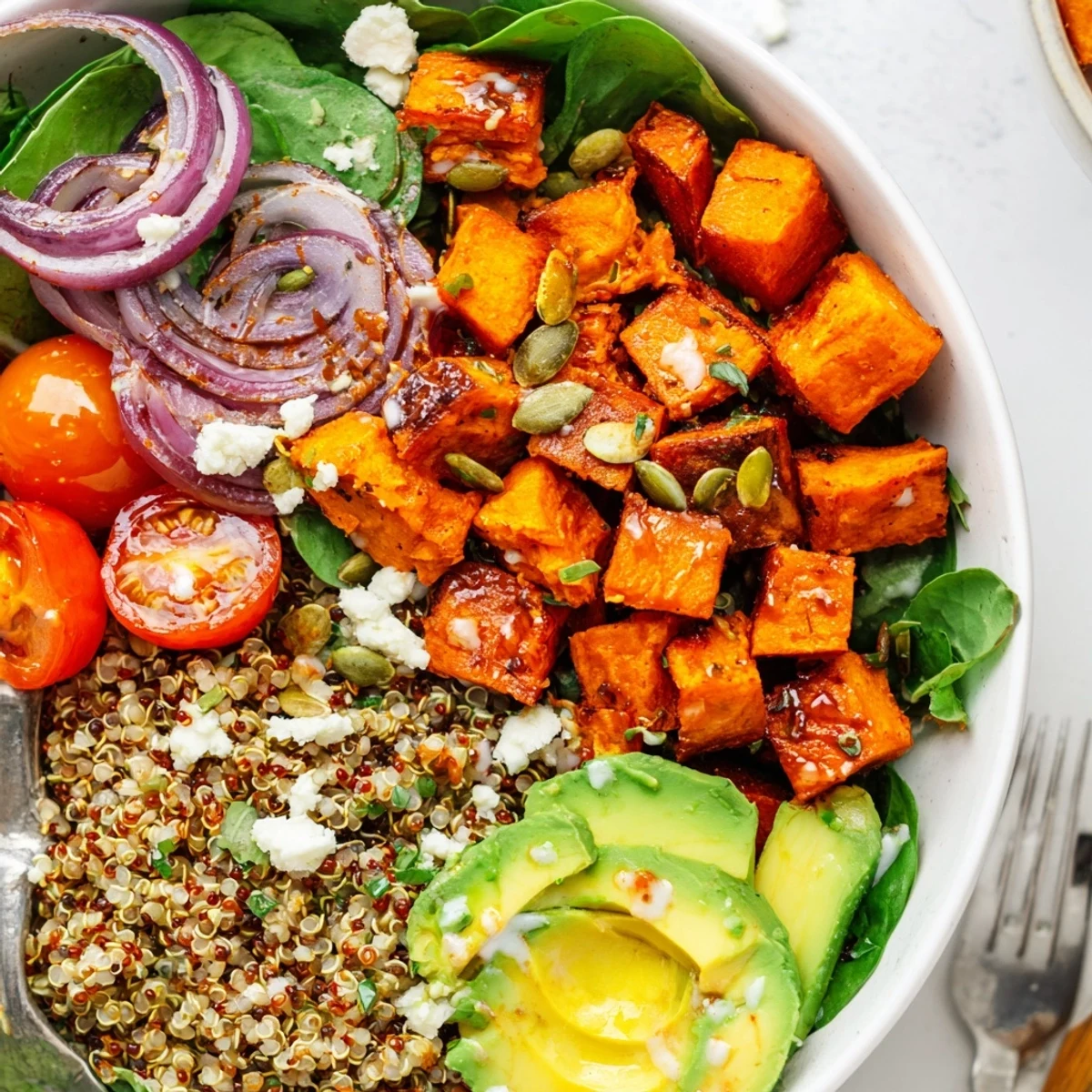 Roasted Sweet Potato Quinoa Salad Bowl served midday with creamy avocado and pumpkin seeds