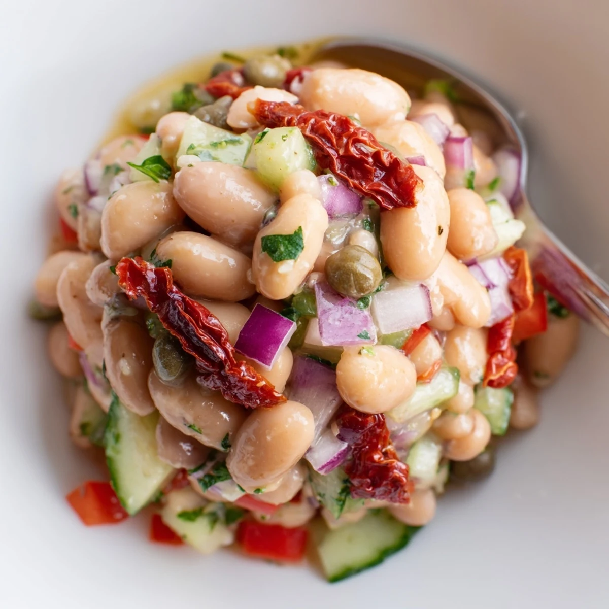 A bowl of Dense Bean Salad With Sun Dried Tomatoes resting to meld flavors.