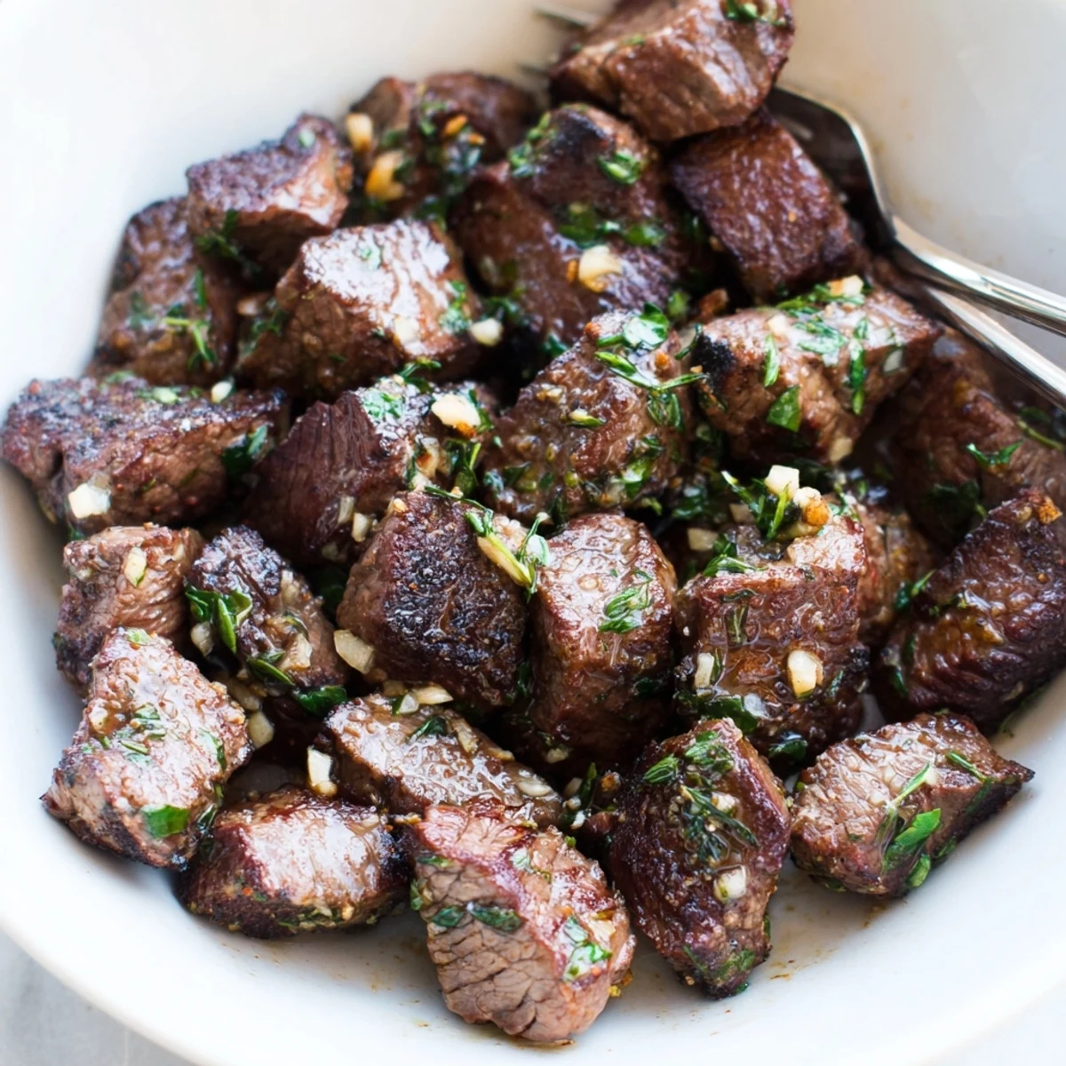 Garlic Butter Steak Bites sizzling in a cast-iron skillet, glossy herb butter