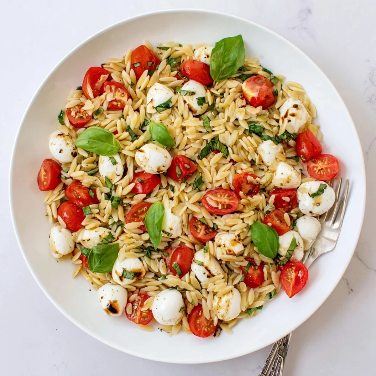 Fresh Caprese Orzo Pasta Salad featuring tender orzo pearls with juicy halved tomatoes and creamy mozzarella coated in balsamic dressing