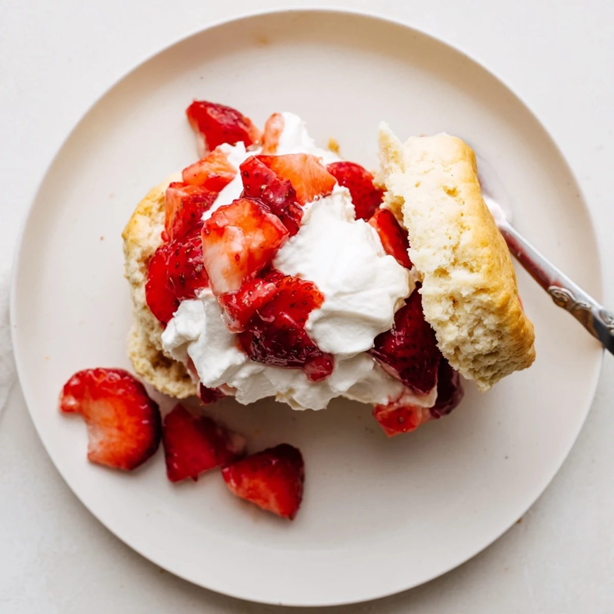 Fresh strawberry shortcake dessert featuring split biscuits topped with macerated berries and sweet cream topping