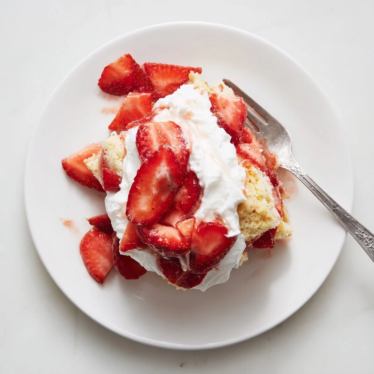 Golden homemade strawberry shortcake stacked with juicy red berries and fluffy white whipped cream