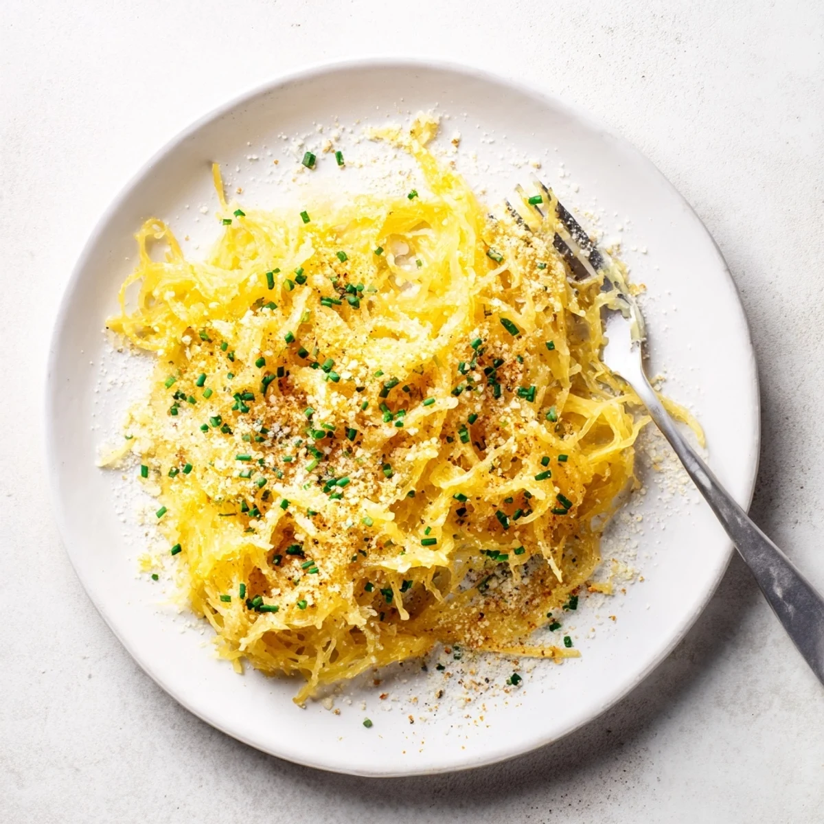 Golden bowl of spaghetti squash mac and cheese topped with crispy breadcrumbs and fresh chives