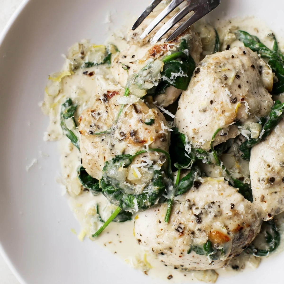 Creamy Lemon Parmesan Spinach Chicken garnished with fresh zest and extra cheese