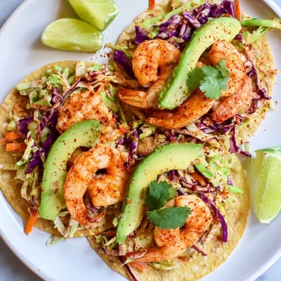 Golden pan-seared spicy shrimp tacos drizzled with creamy garlic cilantro lime slaw