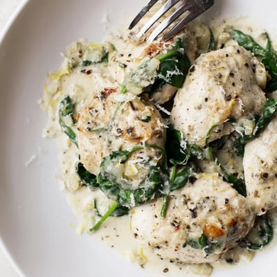 Creamy Lemon Parmesan Spinach Chicken garnished with fresh zest and extra cheese